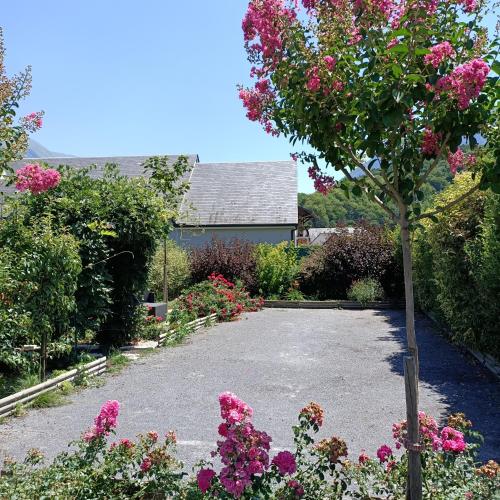 a garden with a tree and pink flowers at Le balcon des cimes in Adast