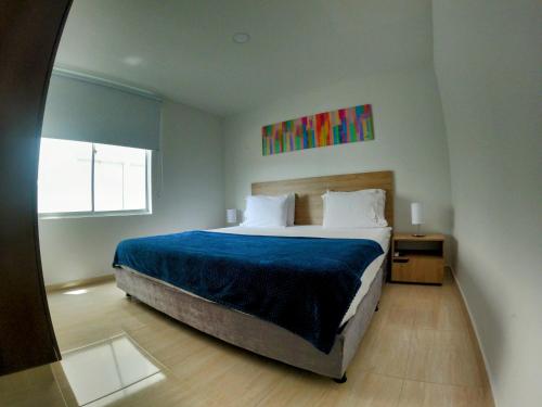 a bedroom with a large bed with a blue blanket at Apartamentos vacacionales San Gil Plaza in San Gil