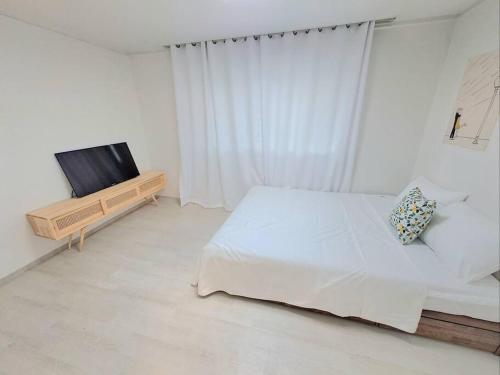 a white bedroom with a bed and a television at Two bedroom Apt Hongik University in Seoul