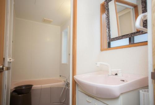 a bathroom with a sink and a mirror and a tub at Nishichaya TABI-NE in Kanazawa