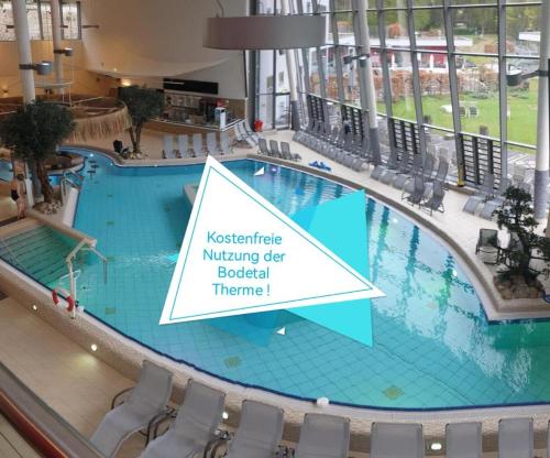 a large swimming pool in a building with a sign that reads restricted swimming dear hospital at Hotelpark Bodetal mit Ferienwohnungen in Thale