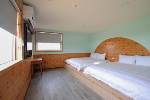 恆春的住宿－峰樹屋，一间卧室设有两张床、一张桌子和一个窗口。