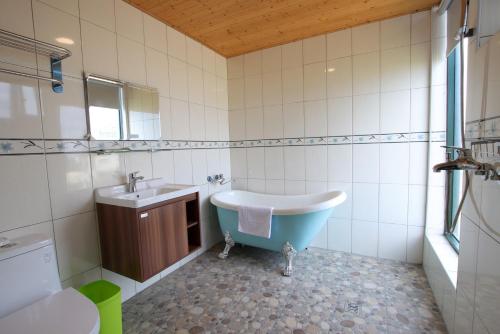 a bathroom with a bath tub and a sink at 峰樹屋 in Hengchun South Gate