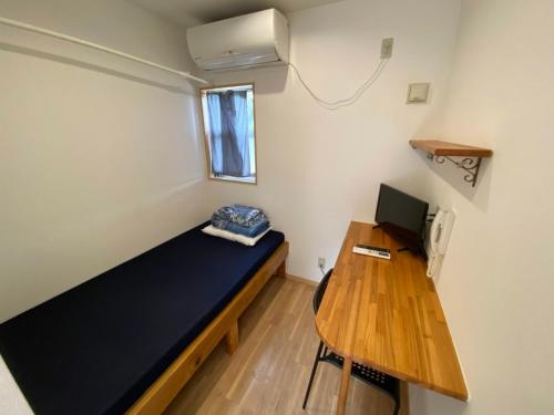 una habitación con una cama y un escritorio con una computadora en House&Cafe GreenTerrace, en Ishigaki Island