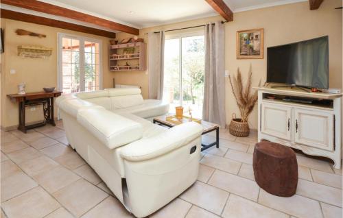 un salon avec un canapé blanc et une télévision dans l'établissement Cozy Home In Méjannes-Lès-Alès, à Méjannes-lès-Alès