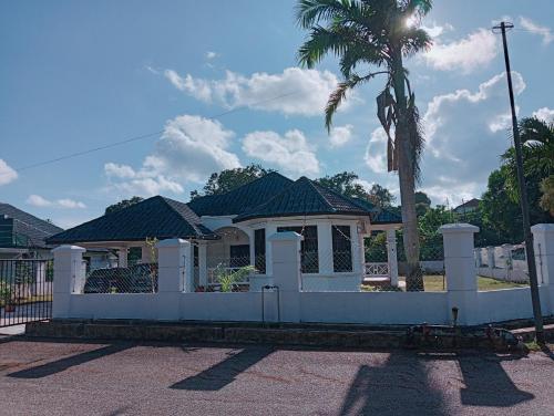 uma cerca branca em frente a uma casa com uma palmeira em The Beach House @ Kuantan em Kuantan