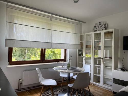 a dining room with a table and chairs and a window at Apartamenty Miły - Gdynia Redłowo in Gdynia