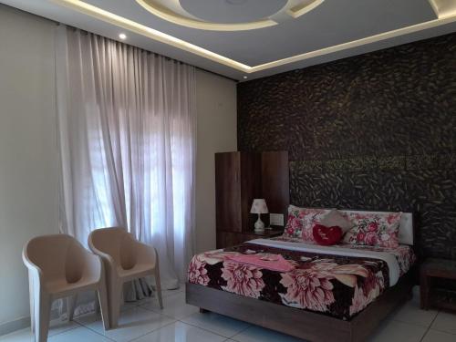 a bedroom with a bed and two chairs and a window at Orchid Ranipuram in Kallar