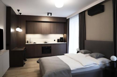 a bedroom with a large bed and a kitchen at Apartamenty Legionów- A12 stylowy apartament w świetnej lokalizacji in Kalisz