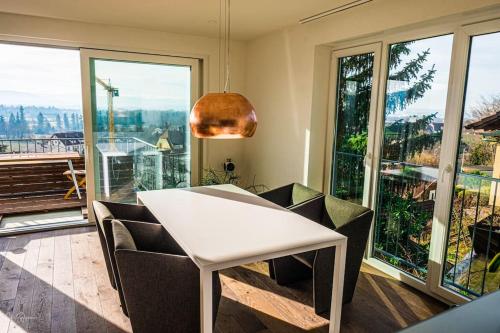a white table and chairs in a room with windows at Panoramahaus am Schlipfweg in Weil am Rhein