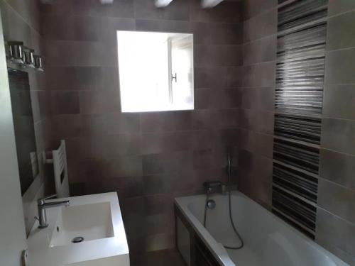 une salle de bain avec une baignoire, un lavabo et une fenêtre dans l'établissement Les 2 p'tits loups, à Osse-en-Aspe