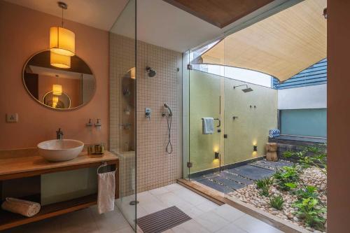 a bathroom with a glass shower and a sink at StayVista at Isle View with Heated Pool in Dabolim