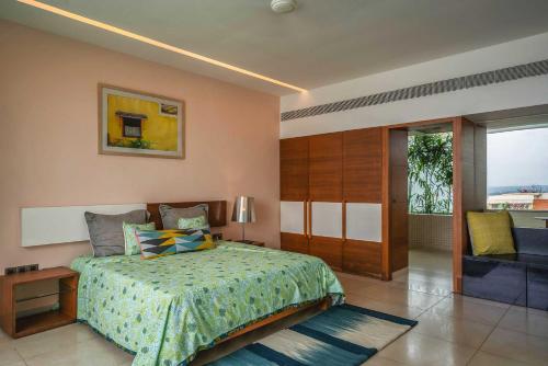a bedroom with a bed and a sliding glass door at StayVista at Isle View with Heated Pool in Dabolim