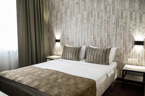 a bedroom with a large bed and two lamps at UYUTNYY DOM in Taraz