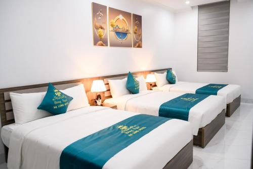 three beds in a room with blue and white at Hồng Ngọc Hạ Long Hotel in Ha Long