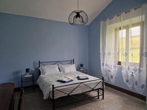 a blue bedroom with a bed and a window at Agriturismo Rossello in San Quirico dʼOrcia