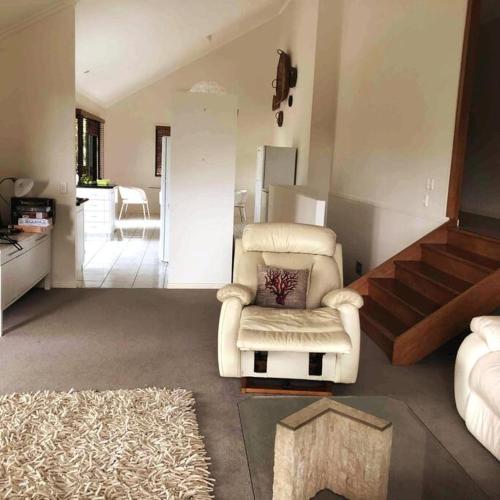 a living room with a white chair and a rug at Noosa hinterland acreage close to the beach in Ninderry