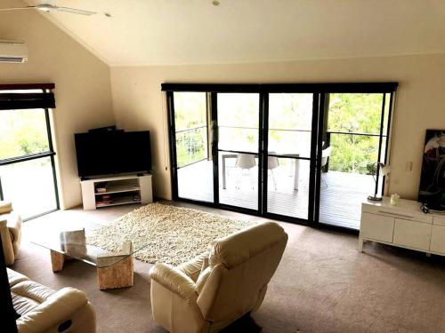 a living room with a couch and a tv at Noosa hinterland acreage close to the beach in Ninderry