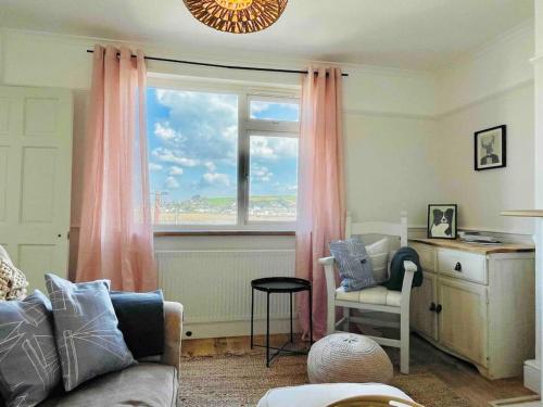 uma sala de estar com uma janela, um sofá e uma cadeira em * Fisherman’s Cottage * with river views (dog friendly!) em Appledore