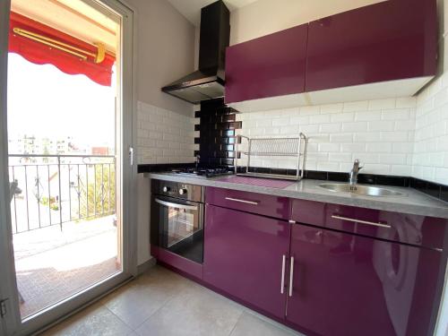 une cuisine violette avec un évier et une fenêtre dans l'établissement Stylish Modern Beach Studio, à Nice