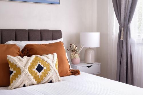 ein Schlafzimmer mit einem Bett mit Kissen und einer Lampe in der Unterkunft JLs Bondi Escape - Walk to beach and Shopping in Sydney