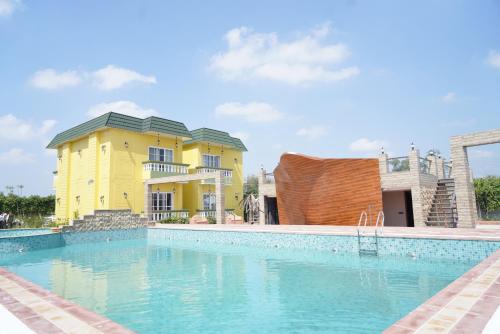 a large swimming pool in front of a yellow house at 5 States Resort in Amritsar