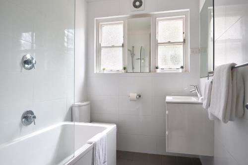 a white bathroom with a tub and a sink at JLs Bondi Escape - Walk to beach and Shopping in Sydney