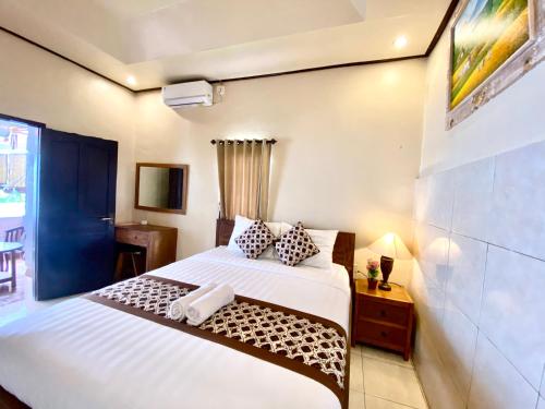 a bedroom with a large white bed and a table at D'JERO HomeStay in Ubud