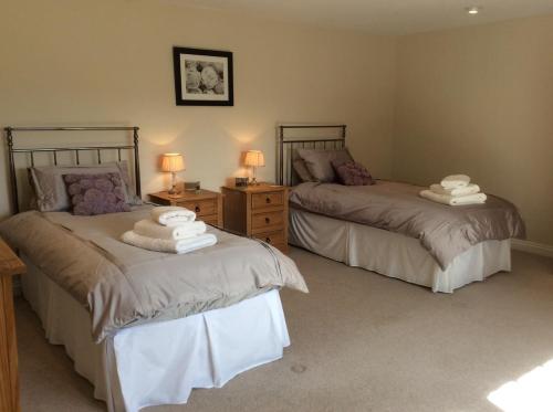 two beds in a bedroom with two lamps on tables at Rock Moor House B&B in North Charlton