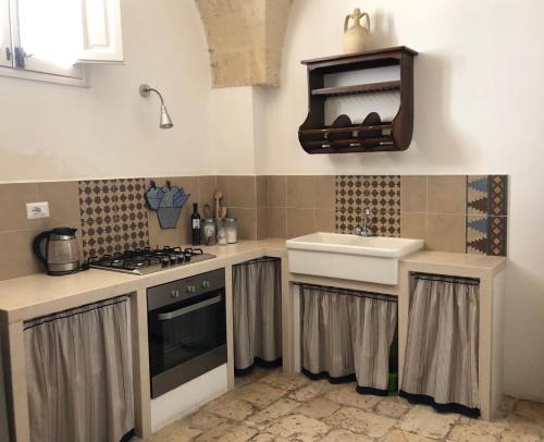 een keuken met een wastafel en een fornuis top oven bij Antica Casa del Pozzo in Manduria