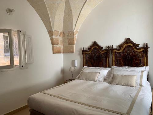 マンドゥーリアにあるAntica Casa del Pozzoのベッドルーム1室(大型ベッド1台、木製ヘッドボード付)