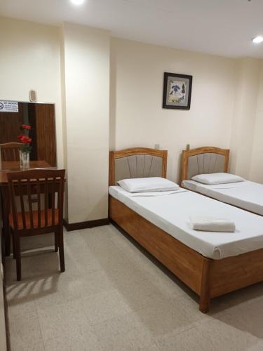 two twin beds in a room with a chair at Mactan Pension House in Mactan