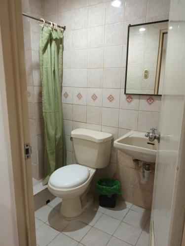 ein Badezimmer mit einem WC, einem Waschbecken und einem Spiegel in der Unterkunft Mactan Pension House in Mactan