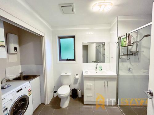 a bathroom with a toilet and a sink and a washing machine at Beige & Beautiful - 1bd 1bth Apt - Close to ANU in Canberra
