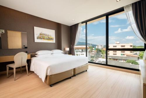 Sanae' Hotel Nimman في شيانغ ماي: غرفة نوم بسرير ومكتب ونوافذ كبيرة