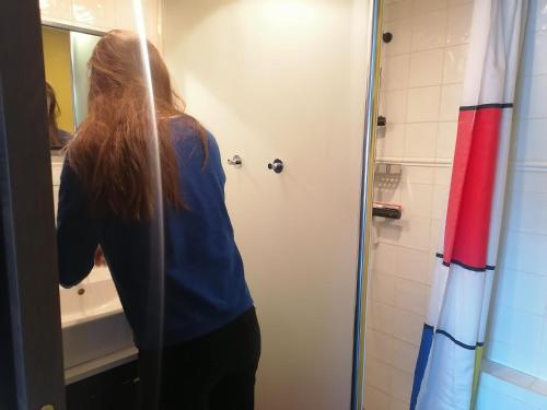 Una mujer mirando su reflejo en un espejo del baño. en Gîte LA Maison LA en Saint-Aubin-dʼAubigné