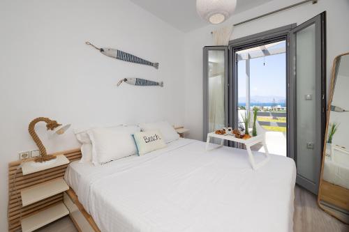 a bedroom with a white bed and a large window at The Nine Graces - Beach Apartment Clea, hot tub and sea views in Agia Anna Naxos