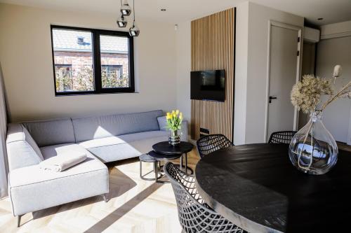 a living room with a couch and a table at Prachtige bungalow op vakantiepark bij zee. in Baarland