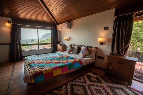 a bedroom with a bed and a large window at Malhar Machi Mountain Resorts in Mulshi