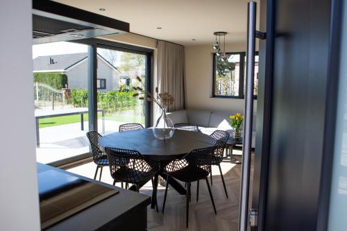 a dining room with a table and chairs at Prachtige bungalow op vakantiepark bij zee. in Baarland