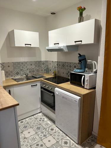 una pequeña cocina con armarios blancos y microondas en Joli appartement proche centre ville, thermes, Aquensis en Bagnères-de-Bigorre