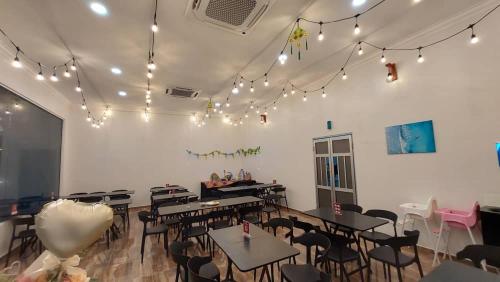a dining room with tables and chairs and lights at Coastal Bay Staycation in Dungun