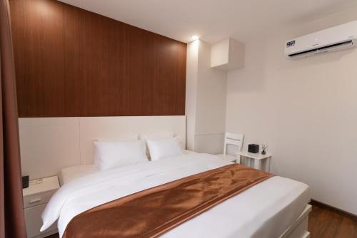 a bedroom with a large white bed with a wooden headboard at Queen Central Hotel - Ben Thanh Market in Ho Chi Minh City