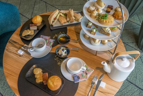 a table with plates of food and cups of tea at Parkhotel Tjaarda in Oranjewoud