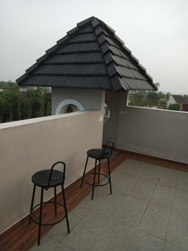 two chairs and a table on a balcony with a roof at IRIS HILL VILLA in Thôn Dương Xuân Hạ