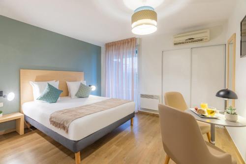 1 dormitorio con 1 cama, mesa y sillas en Appart'City Confort Toulouse Purpan en Toulouse