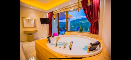 ein Badezimmer mit einer großen Badewanne und einem Fenster in der Unterkunft Villa flamingo in Kaş