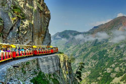 a red and yellow train on a mountain cliff at Apartamentos Lausan in Gavín