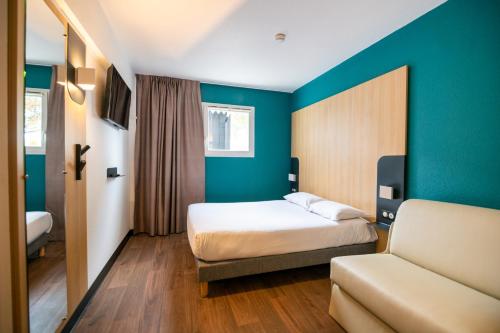 une chambre d'hôtel avec un lit et un canapé dans l'établissement B&B HOTEL Bordeaux Mérignac Aéroport, à Mérignac