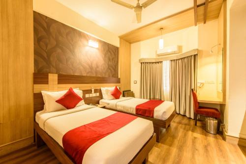 a hotel room with two beds and a chair at Bangalore Gate Hotel & Conferences in Bangalore